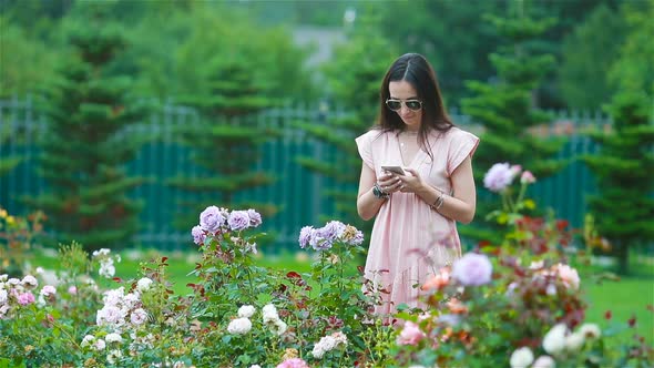 Young Girl in a Flower Garden Among Beautiful Roses. Smell of Roses