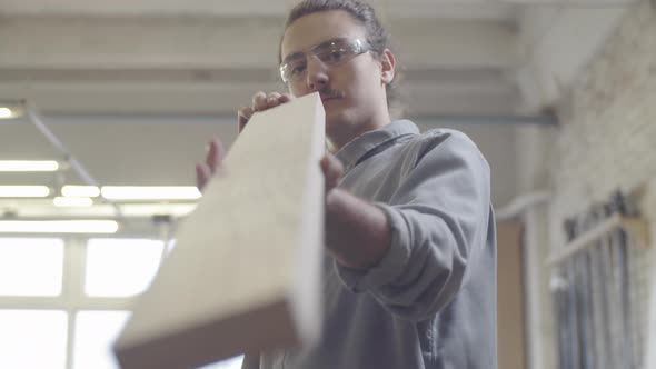 Caucasian Man Checking Trimmed Wood Board at Carpentry Workshop alt