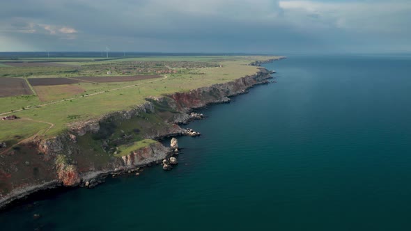 Picturesque rocky coastline with green fields alt