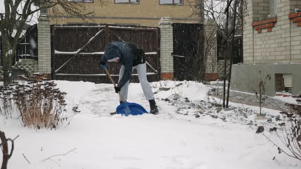 Man is shoveling snow in backyard in snow storm alt