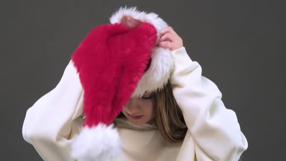 A girl puts on a Santa Claus Christmas hat. Merry Christmas