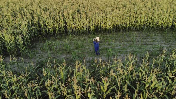 Woman Agronomist in Overalls with an Electronic Tablet in His Hands. An Agricultural Worker Inspects alt