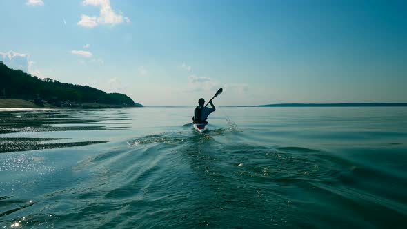 Backside View of a Man Crossing a Lake in a Canoe alt