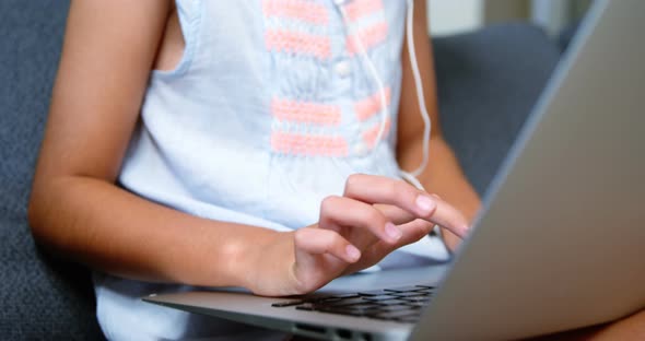 Girl with headphones using laptop in living room alt