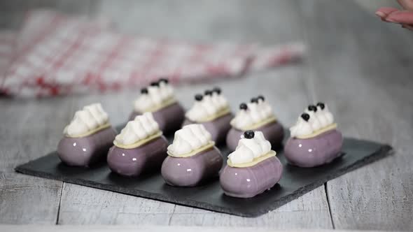 Confectioner decorates mousse cake with a blueberries Production of glazed desserts alt
