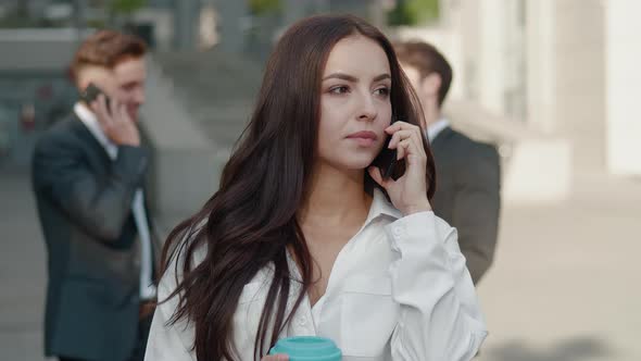 Pretty Young Business Woman Discussing Work on Mobile Phone on Business Center Background. Stylish alt