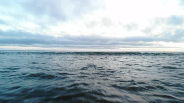 Aerial drone shot flying fast and low over the surface of the Pacific ocean waves crashing on the co alt