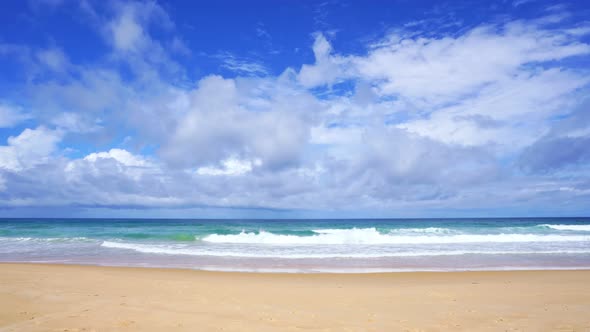 Summer sea background.Blue sky white clouds over ocean waves break on sand beach alt