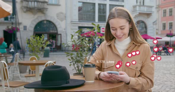 The Girl is Sitting at a Table in a Cafe and Looking Through Their Social Networks alt