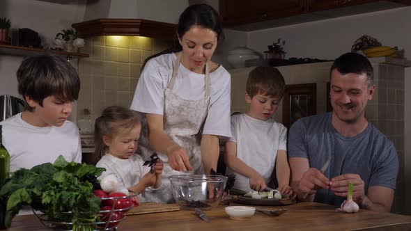 Happy Family with Three Kids is Cooking Salad at Home Together