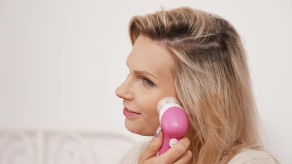 Smiling Caucasian Woman Using Electric Facial Cleansing Brush Closeup alt