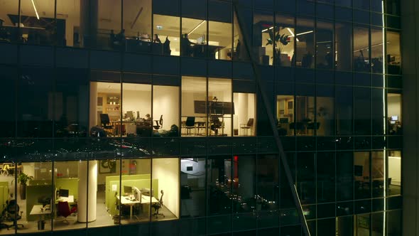 Aerial View of a Night Skyscraper with Siluets of People Working in Offices alt