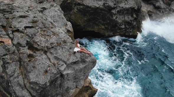 Woman Sitting on the Edge of the Cliff