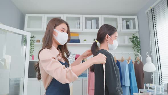 Asian young tailor woman measure customer's body to making her new clothes. alt