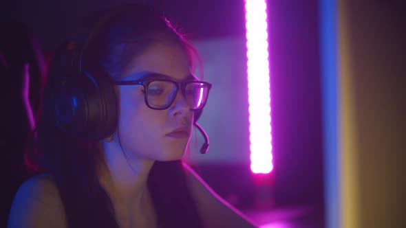 Young Pretty Woman in Glasses Playing Games in Neon Gaming Club alt