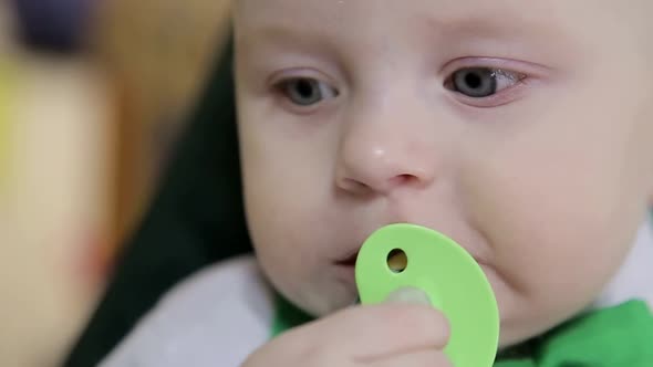 Baby sucks a white nipple lying in his round bed alt