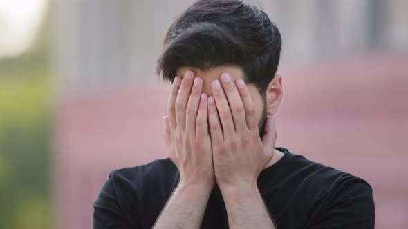 Scared Upset Middle Eastern Bearded Young Man Wearing Black Tshirt Cover Face Feel Frightened alt