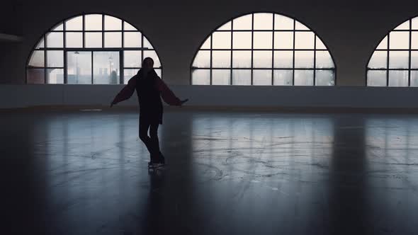 Young Woman Figure Skating Coach Skates on Dark Ice Arena alt