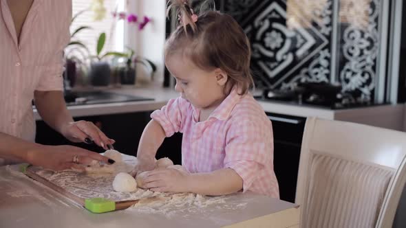 Little Girl Cooking with Caring Mother at Kitchen