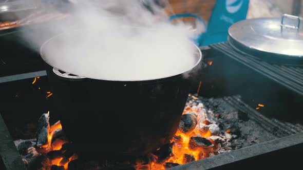 Big Vat of Hot Food Is Cooked on the Coals on a Street Christmas Market alt