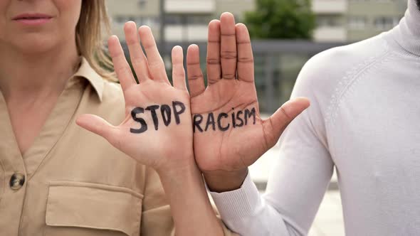 STOP RACISM Written on the Palms of a White Girl and a Black Guy. Stop Racism Concept. alt