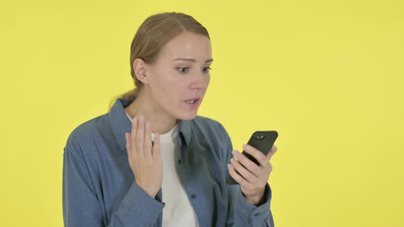 Young Woman Loss on Smartphone on Yellow Background alt