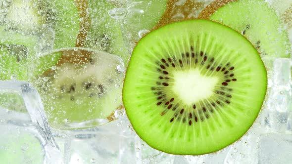 Super Slow Motion Shot of Fizzing Water with Sliced Kiwi and Ice Cubes in Glass at 1000 Fps alt