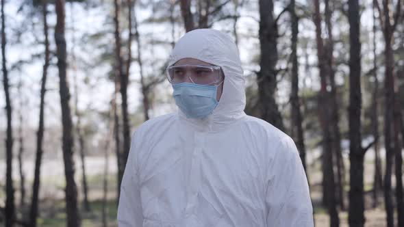 Young Serious Caucasian Man in Safety Suit Walking in City Park. Handsome Boy Wearing Protective alt