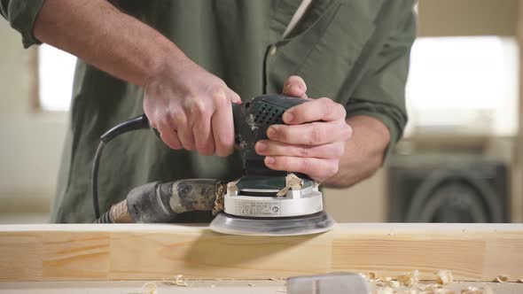 Cropped Male Carpenter Carefully Smoothing Wooden Material with Electrical Sander