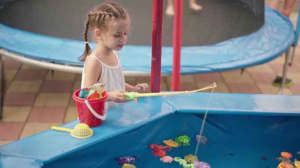 Child Fisher Catching Plastic Toy Fish On Pool Amusement Park Summer Day alt