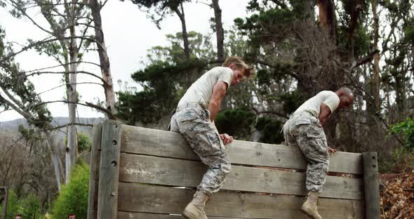 Military people climbing hurdles during obstacle course