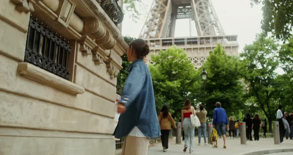 A Young Woman Spinning Around Herself Standing at the Foot of the Eiffel Tower alt