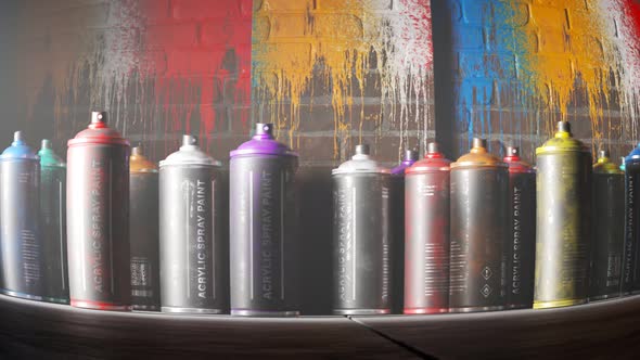 Used, colorful spray paint cans standing in front of a painted brick wall. 4KHD alt