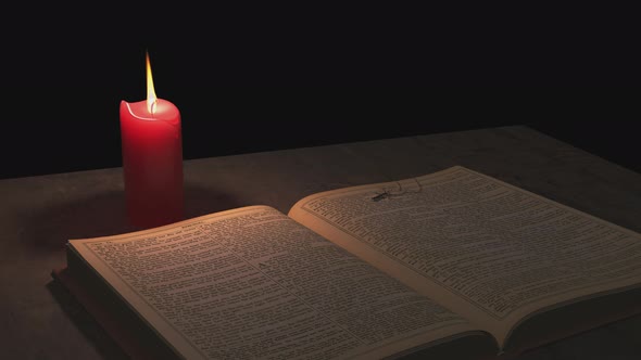 Bible and the Christian cross and a candle burn on a transparent background.
