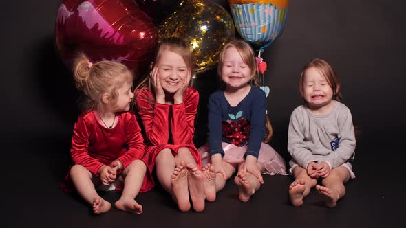 Little Kids Sitting on Floor with Colorful Balloons Behind