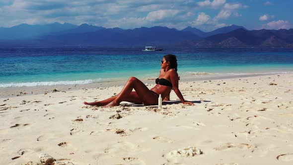 Female models tan on luxury resort beach wildlife by blue sea with white sandy background of Gili Tr alt