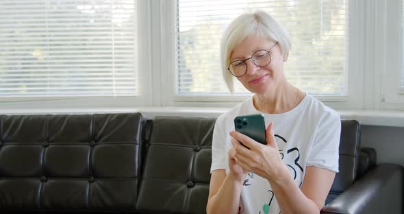 Mature woman using phone. Middle aged woman holding smart phone looking at cellphone screen alt