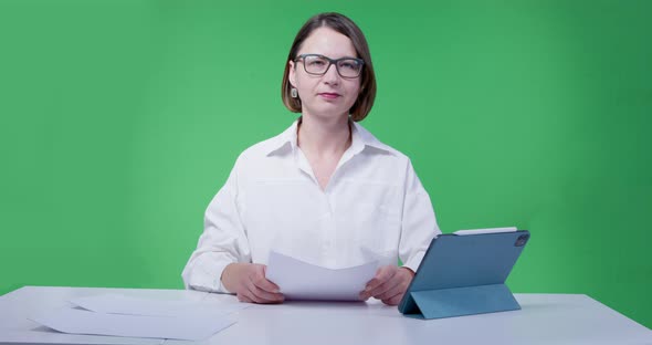 Woman in Glasses and White Shirt Leads a News Release on the TV Channel Green Chromakey on