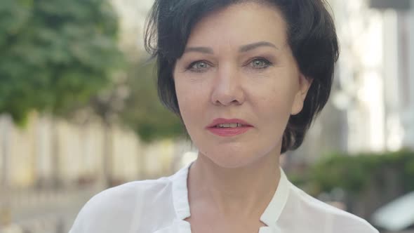 Close-up of Stylish Confident Mid-adult Woman Standing on Urban Street on Summer Day and Looking alt