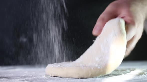 Man takes and rolls out the dough with a rolling pin