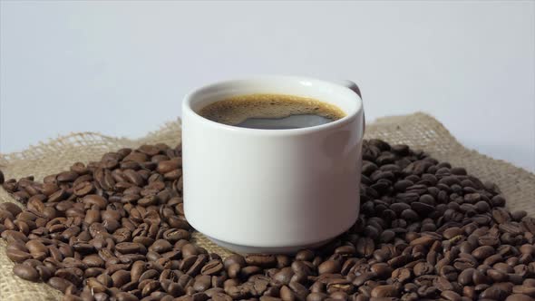 White Cup with Coffee on the Background of Fresh Roasted Coffee Beans