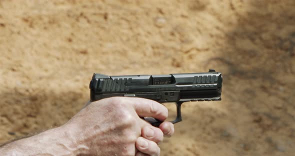 Slow motion of a hand gun firing in a firing range with cartridge flying away alt