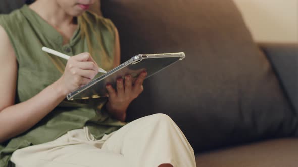 Asian female reading news on her digital tablet.