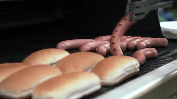 Person Turning Sausages on Grill