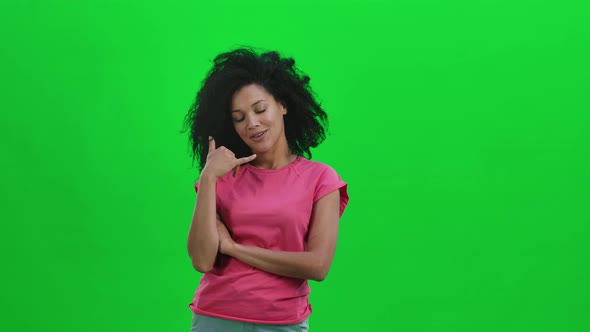 Portrait of Young Female African American Coquettishly Looking at the Camera and Gesturing Call Me alt