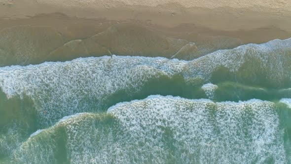 Top Down Aerial View Descending Low Above Powerful Waves Coming onto The Beach