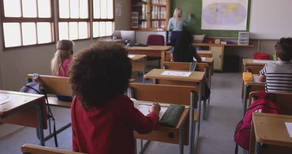 Female teacher teaching group of kids in the class alt