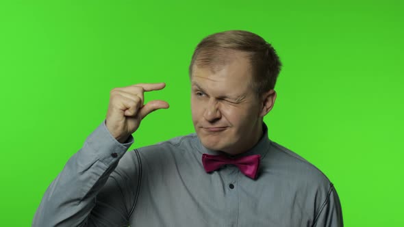 Man Looking at Camera Showing a Little Bit Gesture, Feeling Sceptical About Small Size, Low Scale alt