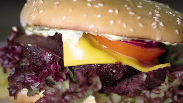 Large Burger with Sliced Steak Roasting Medium Rotating on the Wooden Desk