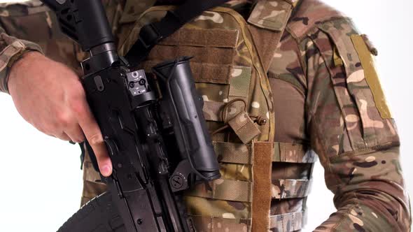 Soldier in modern military outfit picks up a Kalashnikov assault rifle with a collimator sight